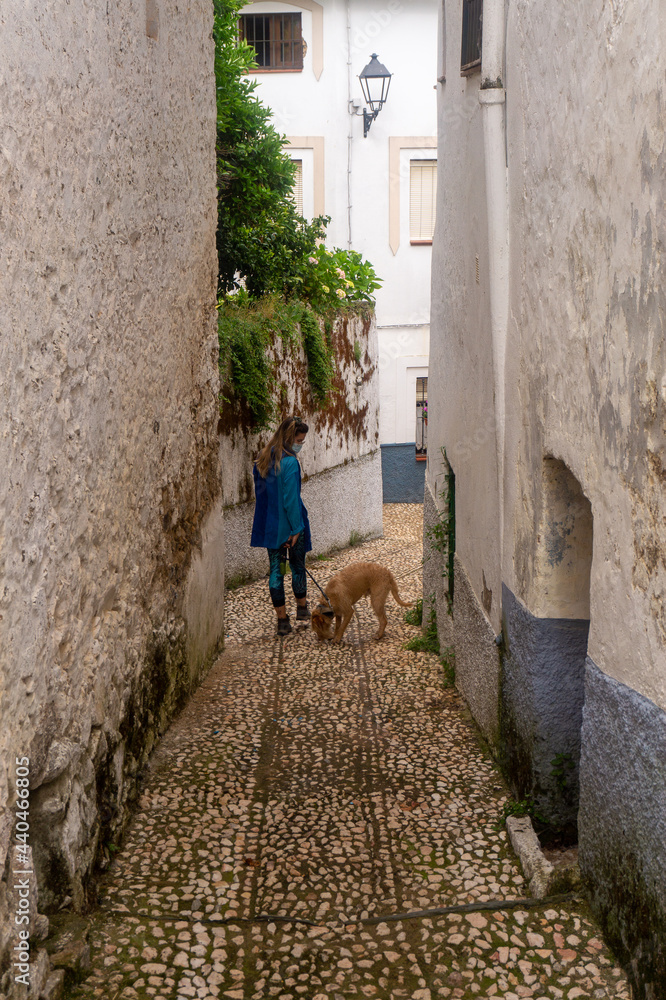 young blonde woman walking with a dog in the street in the old town in Spain young blonde woman walking with a dog in the street in the old town in Spain