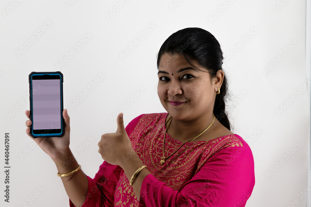 Young beautiful woman holding and showing blank screen smartphone or mobile or tablet phone on a white background with empty space available.. Young beautiful woman holding and showing blank screen smartphone or mobile or tablet phone on a white background with empty space available..