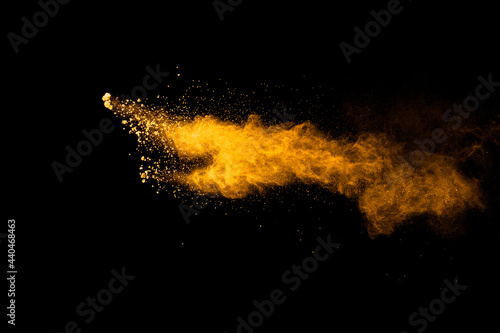 Abstract explosion of orange dust on black background.Freeze motion of orange powder burst.