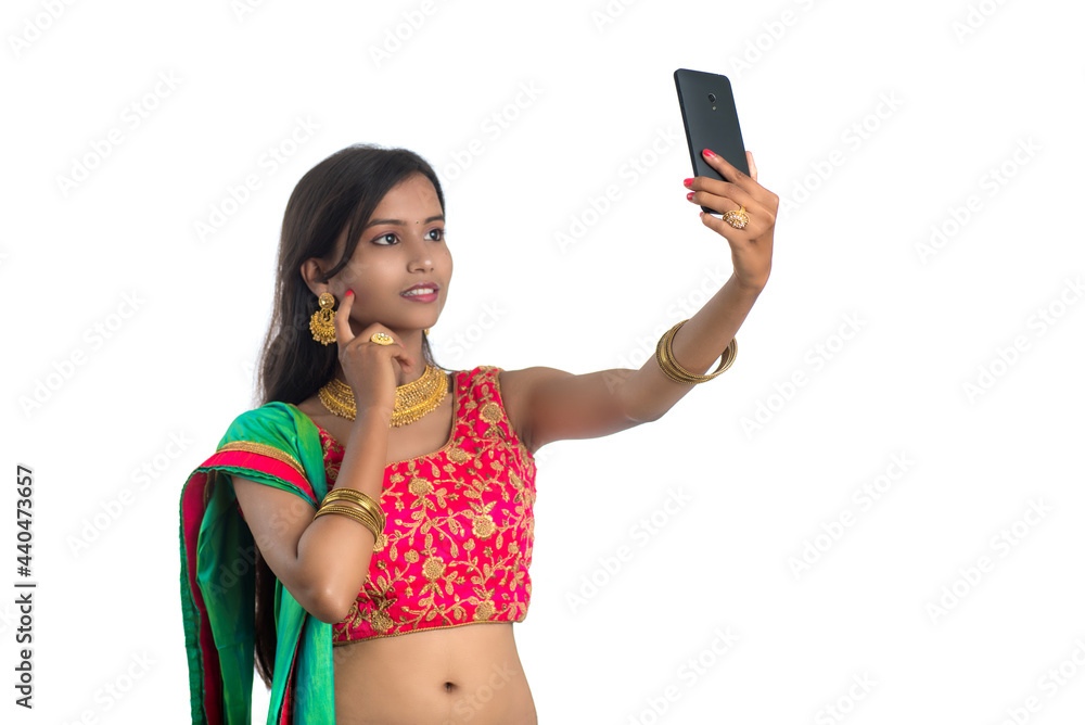 Young Indian girl using a mobile phone or smartphone, talking selfie or talking on video chat isolated on a white background
