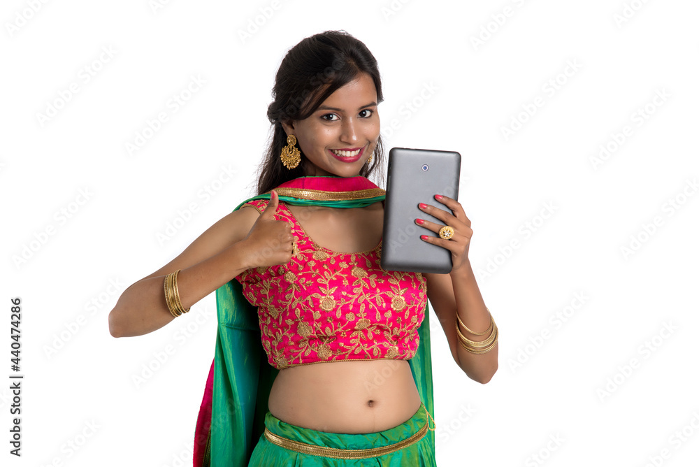 Young Indian traditional girl using a mobile phone or smartphone isolated on a white background Young Indian traditional girl using a mobile phone or smartphone isolated on a white background