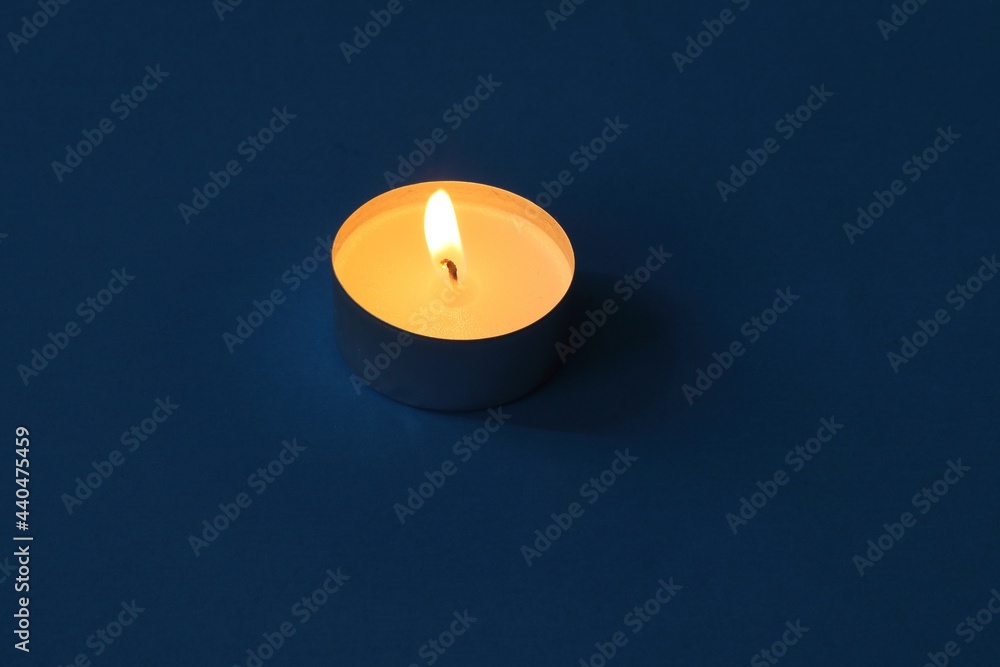 Burning Tealight Candle Against a Dark Blue Background Burning Tealight Candle Against a Dark Blue Background