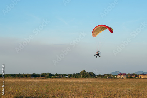 Hang glider with motor in the blue sky on landing