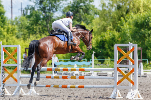 Young horse rider girl jumping on show jumping
