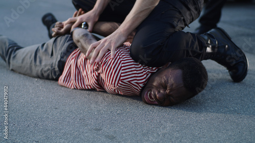 Foto Policeman putting handcuffs on crying black man