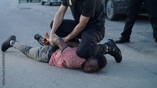 Policeman putting handcuffs on crying black man photo