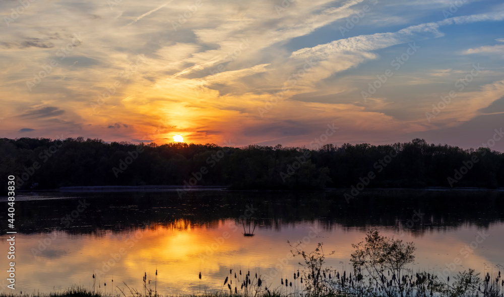 Naklejka premium Sunset with dramatic clouds in sky over lake