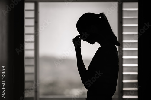 Silhouette of depressed young woman indoors feeling tired. Overworked, sadness concept. 