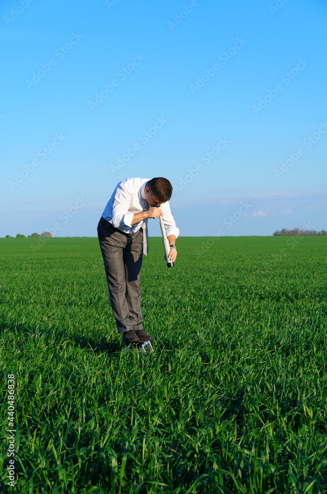 businessman poses with a spyglass in a green field, he looks an idea or something, business concept, green grass and blue sky as background businessman poses with a spyglass in a green field, he looks an idea or something, business concept, green grass and blue sky as background