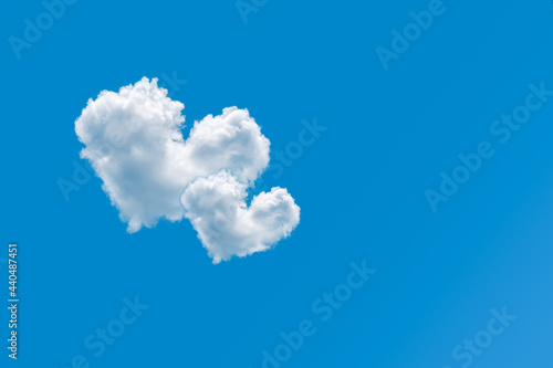 Couple of heart shaped clouds on a clear blue sky background. Concept of love and romance. Pair of cloud hearts in sky. Valentine's day design element. Greeting card with copy space. Love symbol.