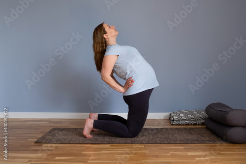 Full length healthy pregnant woman doing yoga exercising stretching at home