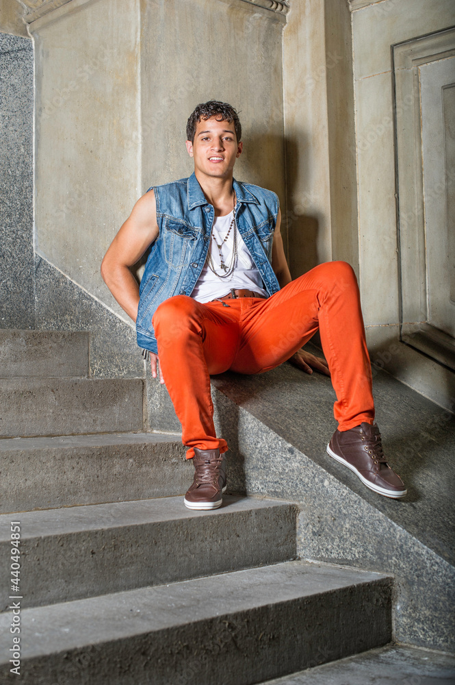 A young guy, sitting outside and against a wall, is looking at you. A young guy, sitting outside and against a wall, is looking at you.