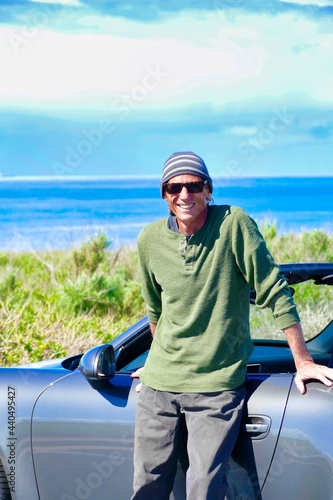 man leaning against car parked at the beach