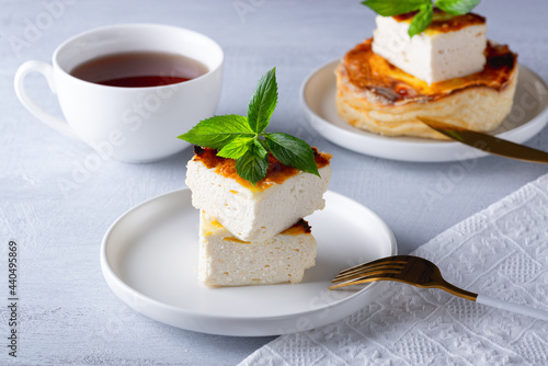 Cottage cheese casserole and cup of coffee on wooden light table. Cottage cheese casserole