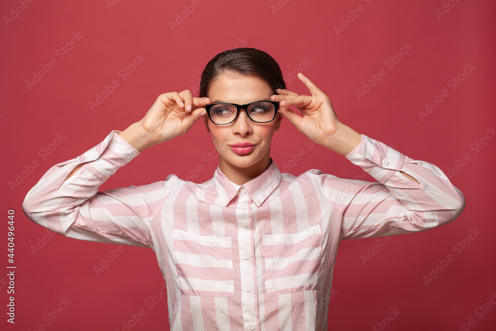 Fototapeta premium Young cheerful woman in glasses smiling on red background