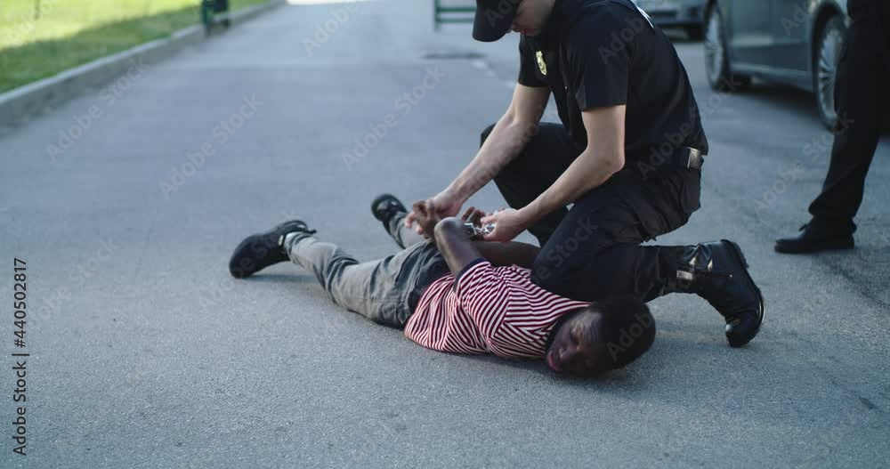 Policeman putting handcuffs on crying black man