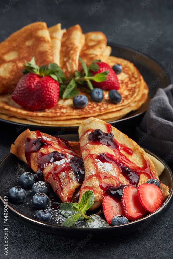 Pancakes with berries and sweet sauce on black background. Maslenitsa. Shrovetide. Shrove Tuesday. Pancake Day. Pancakes with berries and sweet sauce on black background. Maslenitsa. Shrovetide. Shrove Tuesday. Pancake Day.