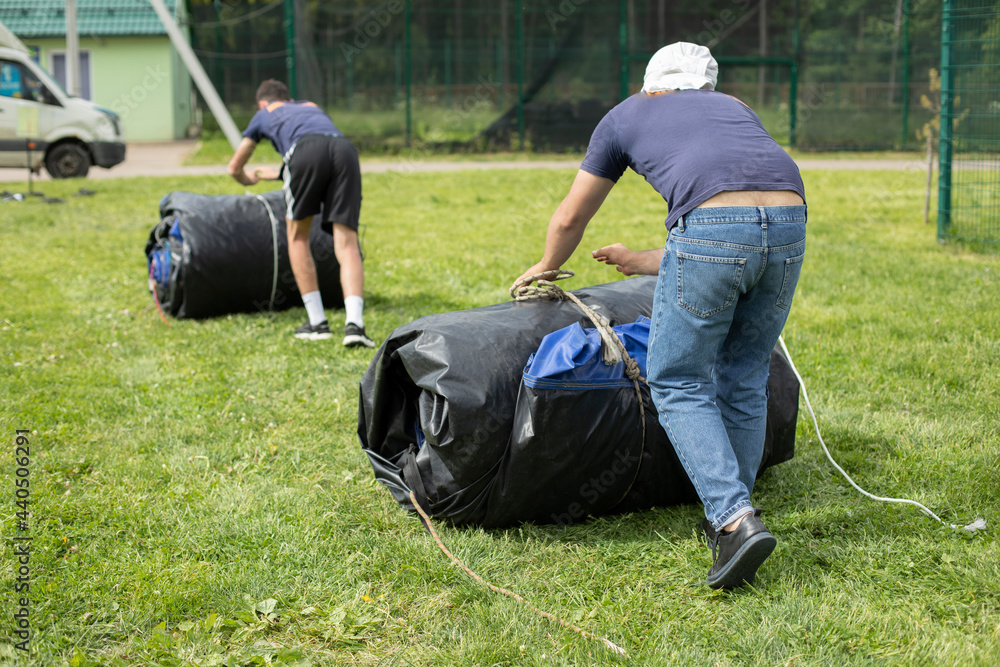 Men drag the weight. Demolition of the event. Loading a twisted awning. Men drag the weight. Demolition of the event. Loading a twisted awning.