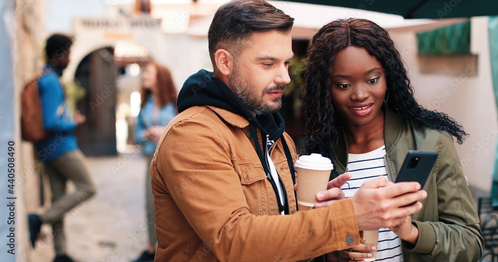 Obraz premium So fun. Waist up portrait view of the curly ginger woman drinking coffee and discussing something at the tablet with her best friend at the city street. Stock video