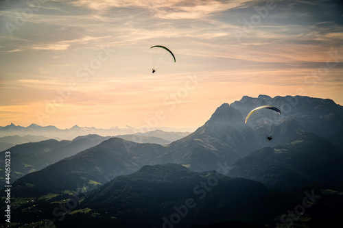 Mesmerizing view of two paragliders flying over the Austrian alps during sunset photo