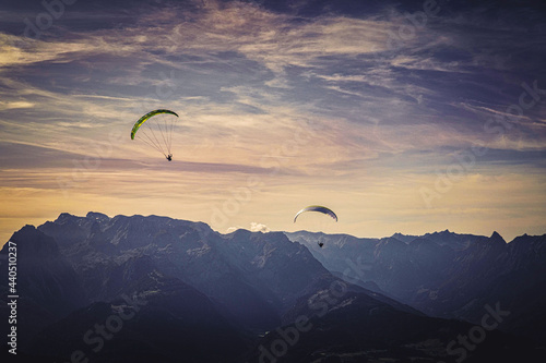 Mesmerizing view of two paragliders flying over the Austrian alps during sunset