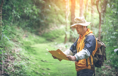 hiker with backpack checks map to find directions in wilderness area