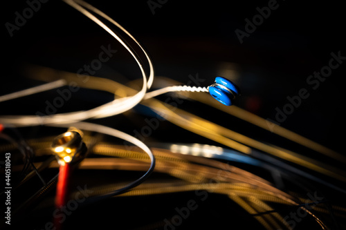 Macro Closeup of Blue Ball End of Bronze Acoustic Guitar String in Front of Group of Loose Used Strings