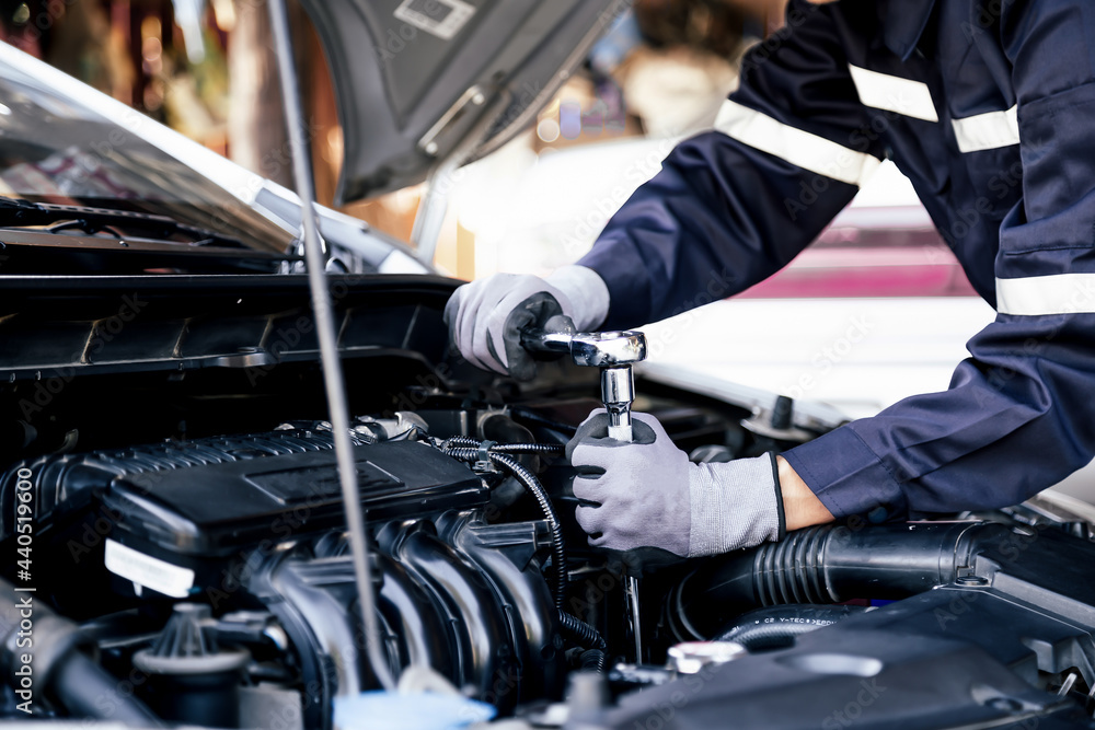 Professional mechanic working on the engine of the car in the garage. Car repair service. The concept of checking the readiness of the car before leaving. Professional mechanic working on the engine of the car in the garage. Car repair service. The concept of checking the readiness of the car before leaving.