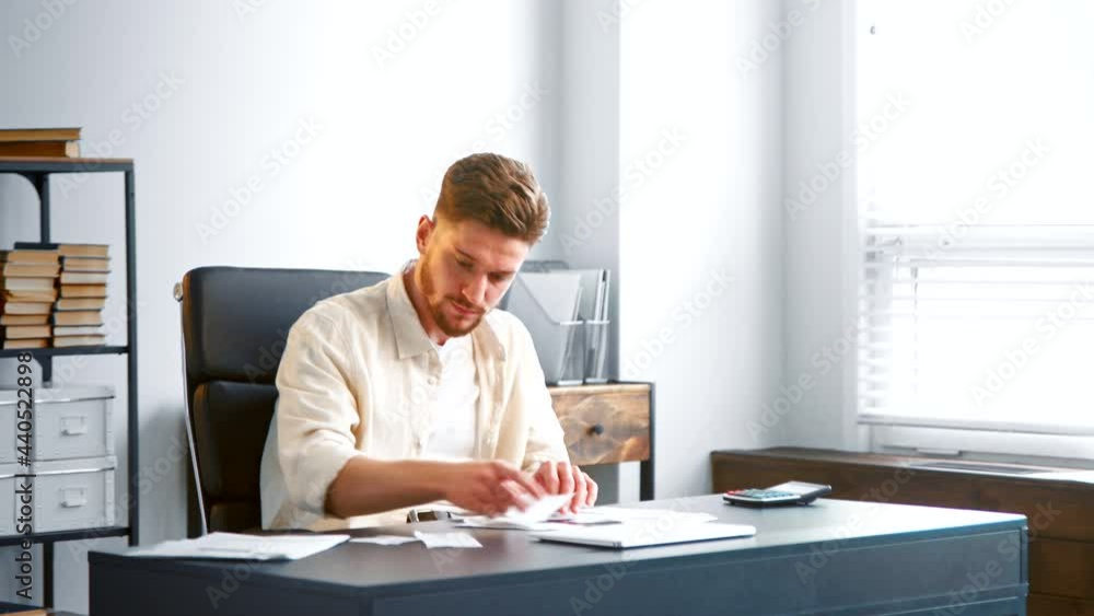 Male manager assistant with beard sorts checks at table Male manager assistant with beard sorts checks at table