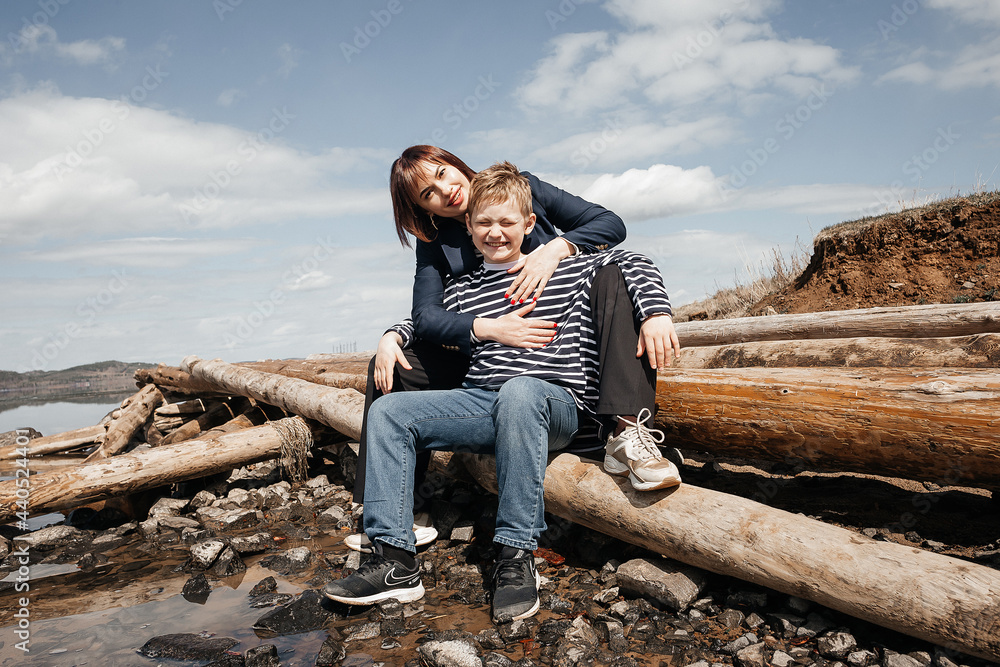 Mom hugs her son on the riverbank.