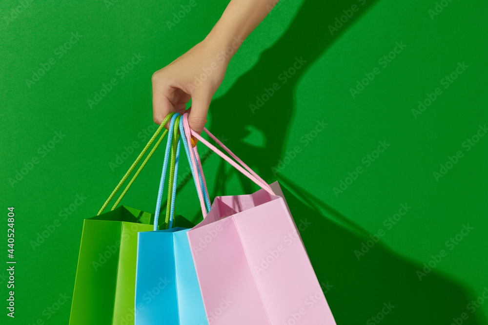 Womans hand holding shopping bags on green background. Shopping sale concept