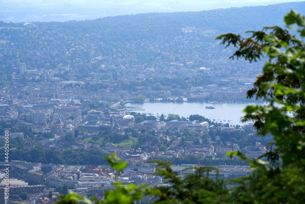 Panoramic view over City of Zurich seen with lake Zurich seen from local mountain Uetliberg on a hazy summer day. Photo taken June 18th, 2021, Zurich, Switzerland.