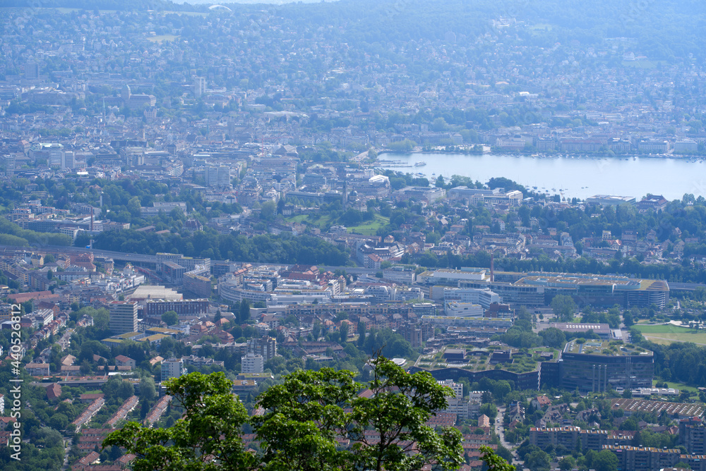 Obraz premium Panoramic view over City of Zurich seen with lake Zurich seen from local mountain Uetliberg on a hazy summer day. Photo taken June 18th, 2021, Zurich, Switzerland.