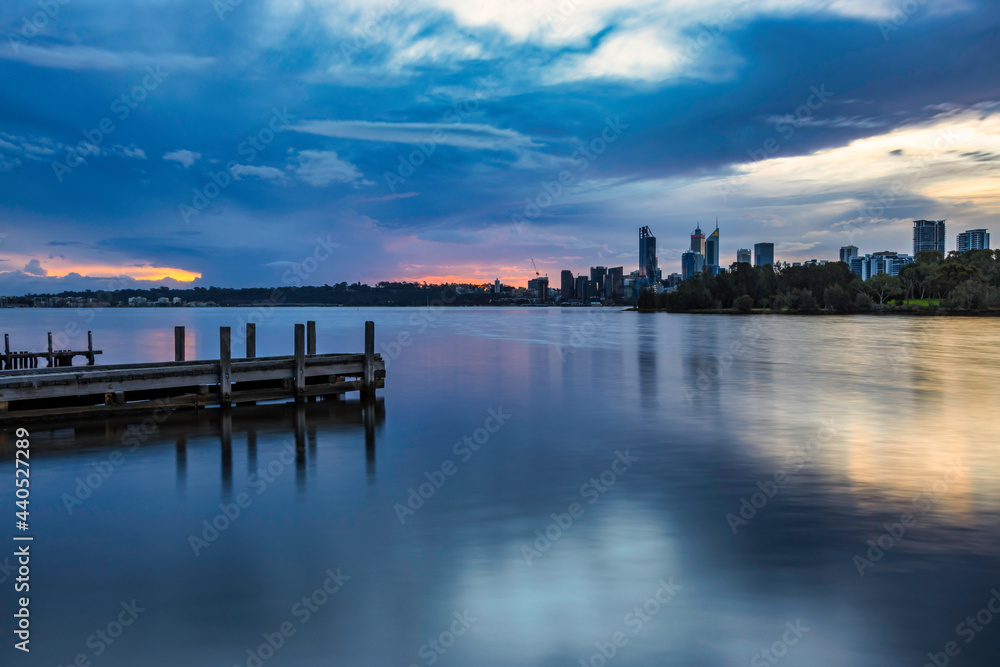 Blue hour sunset, at Swan River, with jetty in foreground and Perth city in background 