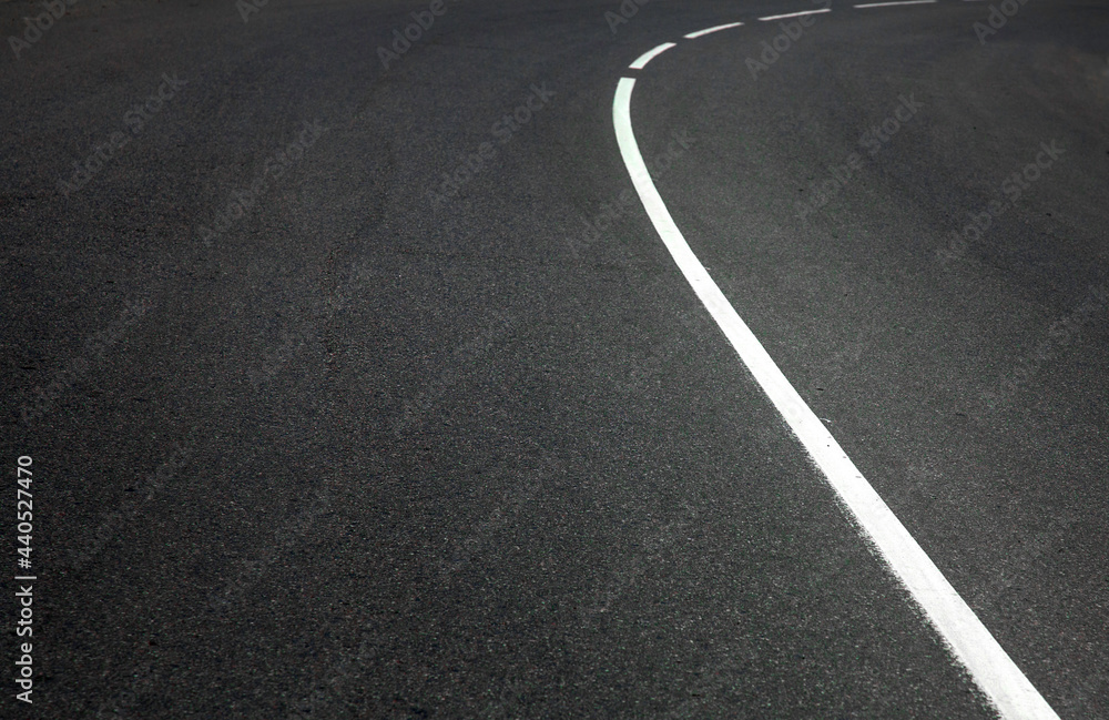 Obraz premium Turning asphalt road with marking lines and tire tracks.