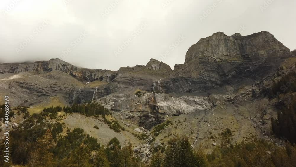 Clouds and waterfalls work themselves down the side of an alpine mountain range in Switzerland Clouds and waterfalls work themselves down the side of an alpine mountain range in Switzerland