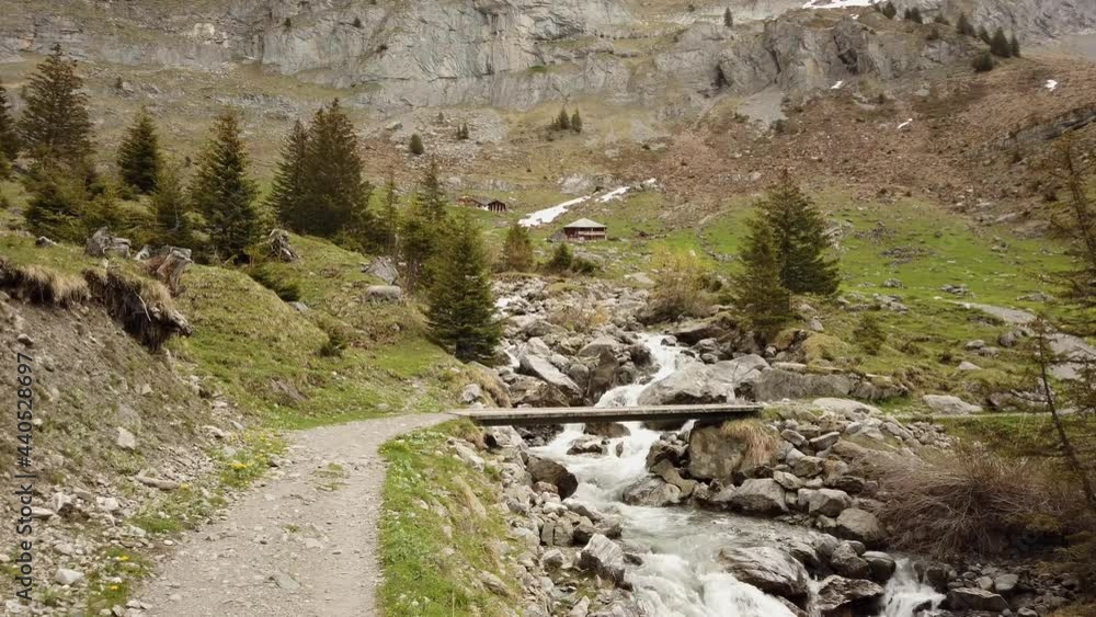 Hiking trail crossing river via little bridge in the Swiss Alps
