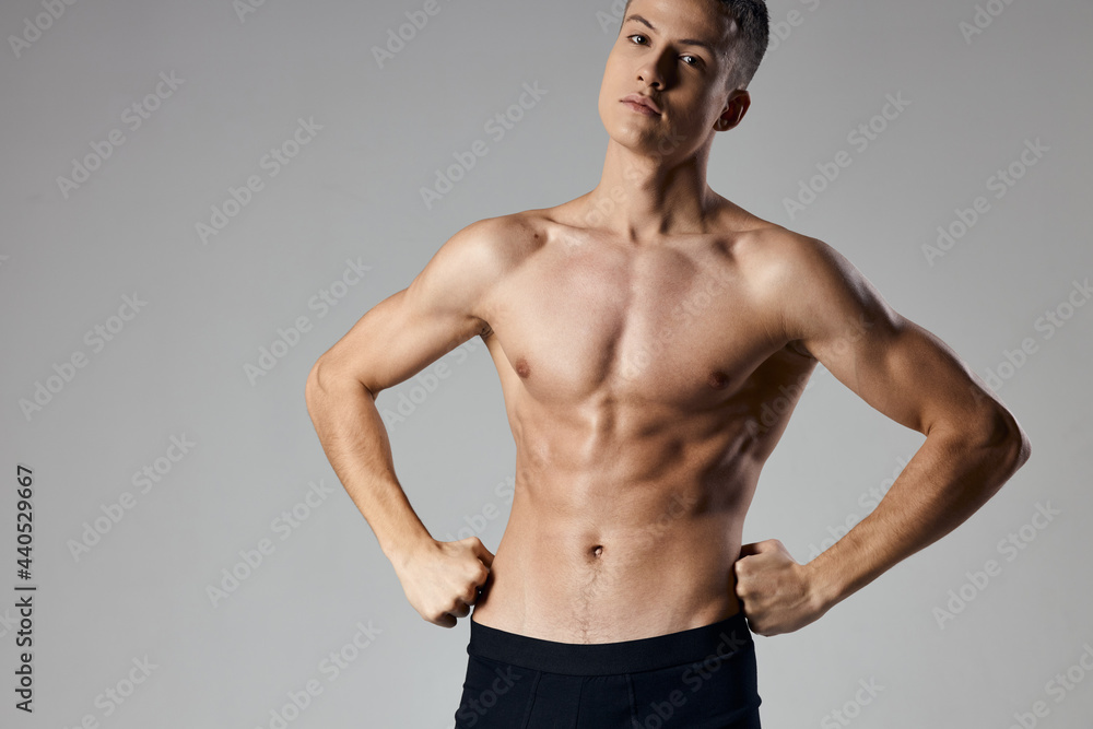 sexy bodybuilder inflated torso holds hands at the waist on a gray background sexy bodybuilder inflated torso holds hands at the waist on a gray background