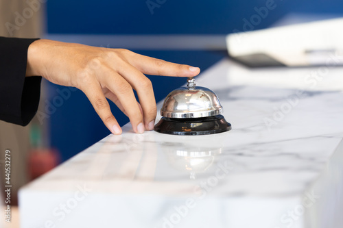 Ring bell call service with hand on hotel reception desk
