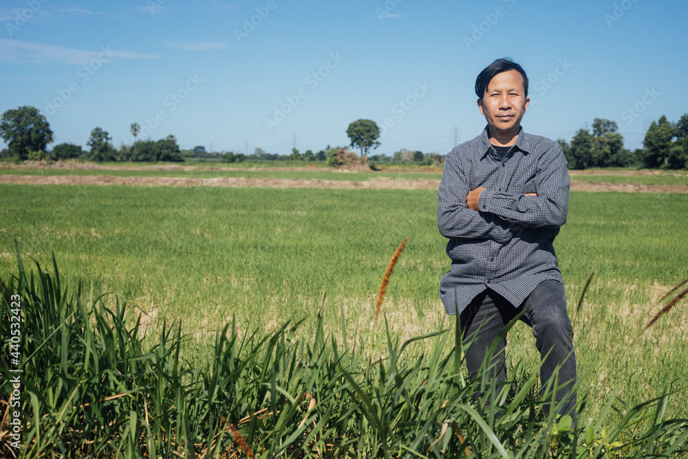 A modern farmer stands proud of his farmland in bright sunlight during the day.