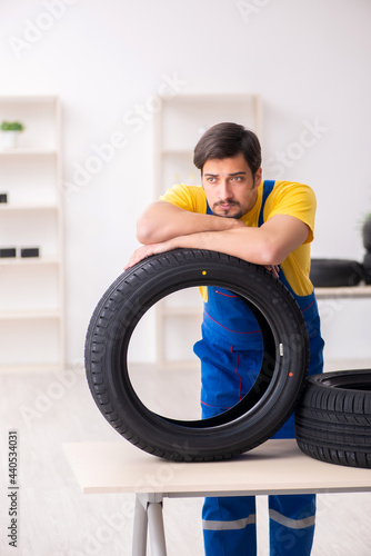 Young male garage worker with tyre at workshop