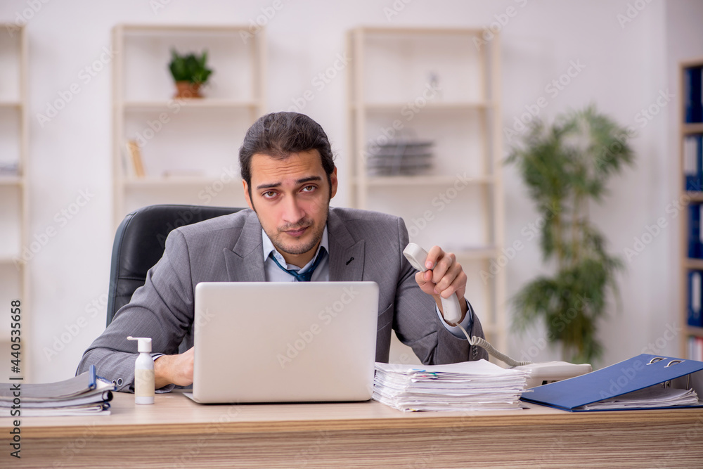 Young male employee unhappy with excessive work in the office Young male employee unhappy with excessive work in the office