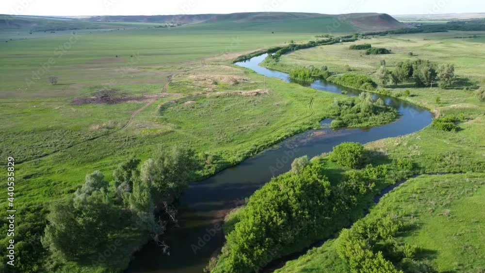 Beautiful landscape. The river flows through green meadows and fields. Hills in the distance. The blue sky is reflected in the water. The video was made from a drone. Beautiful landscape. The river flows through green meadows and fields. Hills in the distance. The blue sky is reflected in the water. The video was made from a drone.