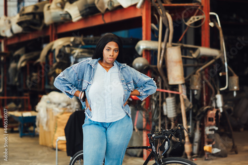 Big african american woman modeling. Old Machine auto parts in warehouses. Auto mechanic car service, repair and maintenance concept. used car-auto mobile spare parts