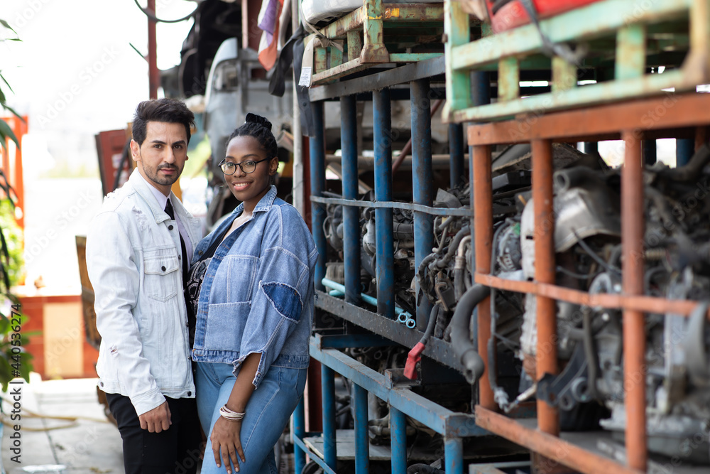 Modeling portrait photo. African American female employee worker and hispanic man manager working together at old auto and car parts warehouse store.