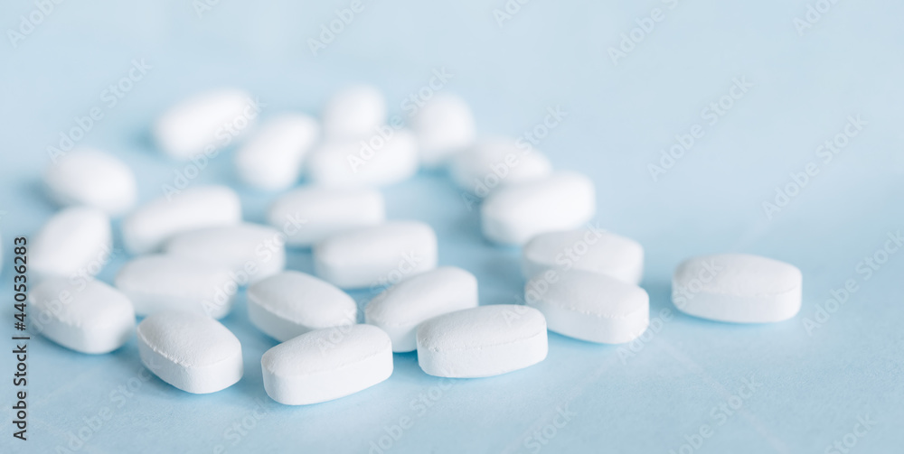 White pills on a light blue background. Healthcare and medicine.	
