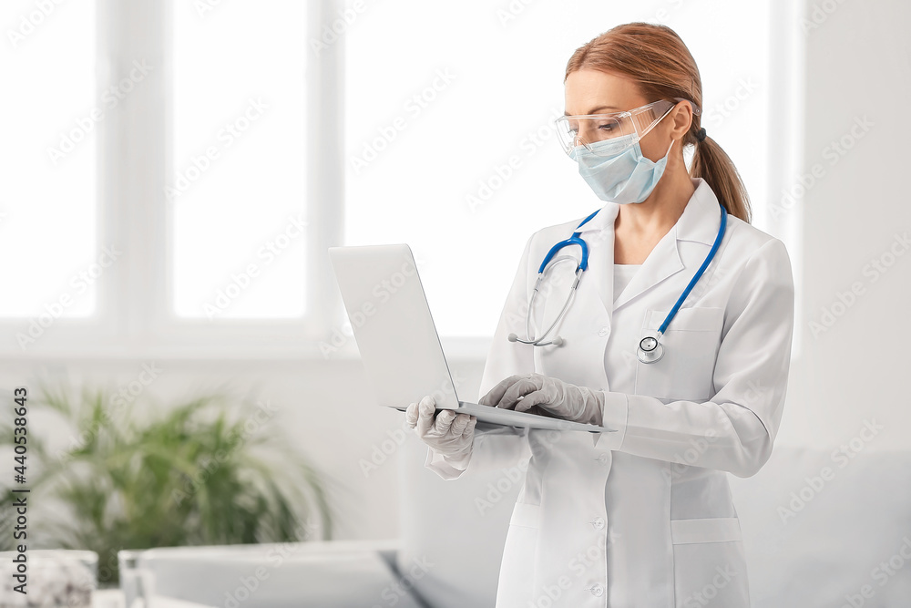 Portrait of female doctor with protective uniform and laptop indoors Portrait of female doctor with protective uniform and laptop indoors
