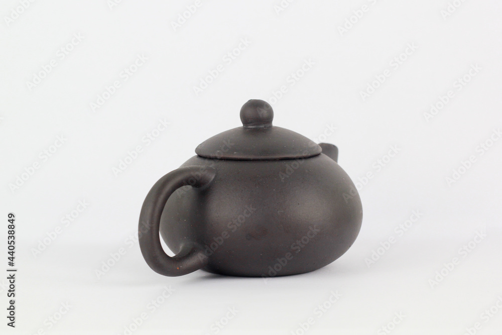 A Chinese black ceramic teapot and teacup isolated on a white background. A Chinese black ceramic teapot and teacup isolated on a white background.