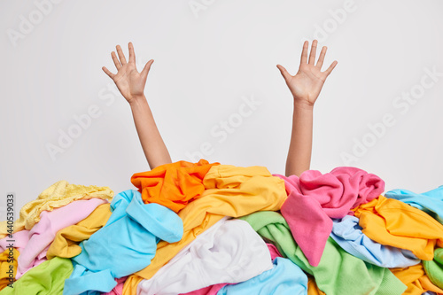 Photo Human hands reaching out from big pile of colorful unfolded clothes against white studio background