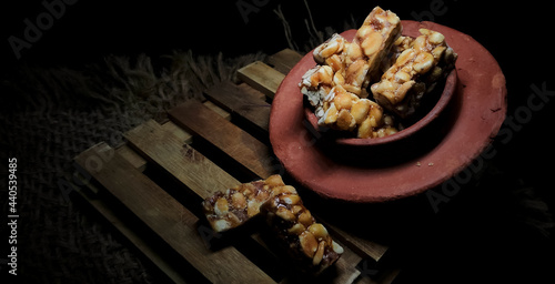 Closeup of peanut bar or peanut chikki made with groundnut and jaggery. Placed in a isolated rustic wooden background. Indian sweet. Protein rich content.  photo